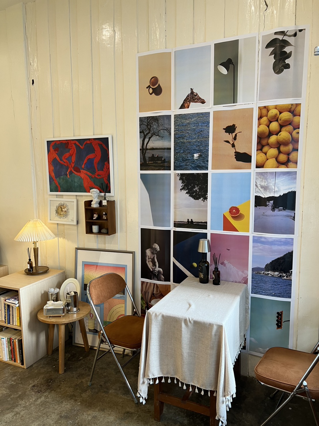 Interior corner with cushioned chair, small table and art prints on the wall